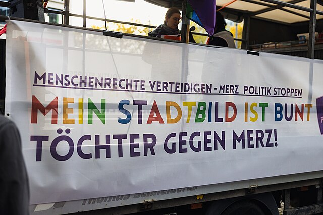 A banner with the statement "Mein Stadtbild ist bunt - Toechter gegen Merz!"