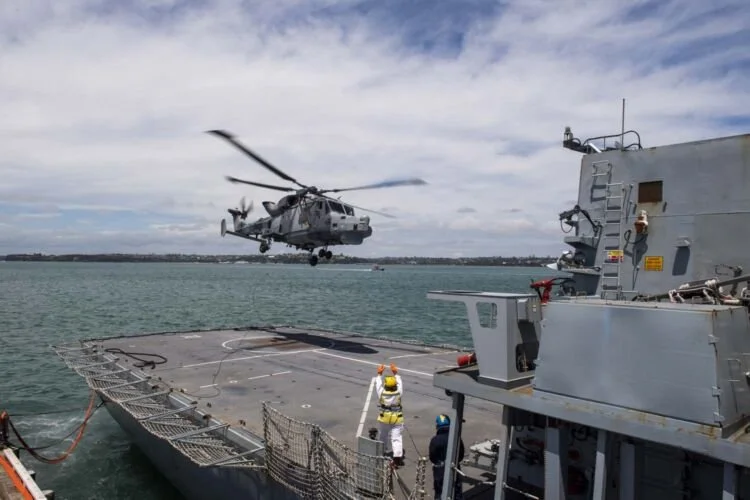 A helicopter lands on an airstrip on a U.S. warship.